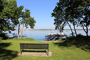 A park bench framed by trees in the City of Monona looks out over the water.