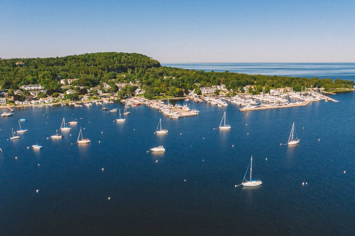An aerial view of the coastline of Door County with dozens of sailboats in the water.